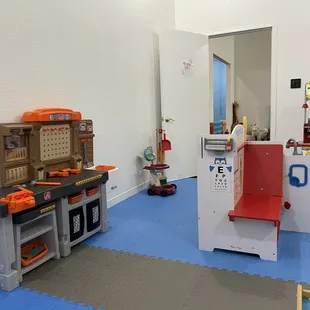 Realistic play room with all kinds of things like a kitchen, doctors office, cleaning supplies, train set, school bus tent