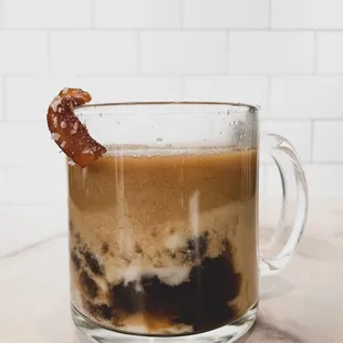 a cup of coffee with a bacon stick sticking out of it