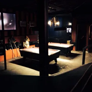 two pool tables in a dimly lit room