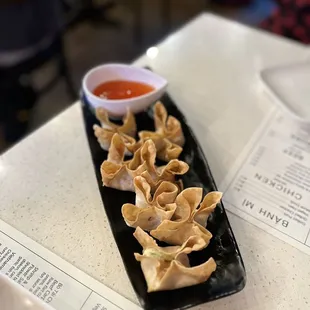 a plate of wontons with dipping sauce