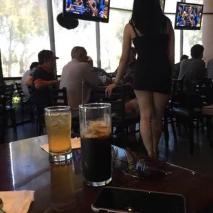 a woman in a black dress standing in front of a bar