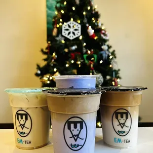 three cups of iced coffee in front of a christmas tree
