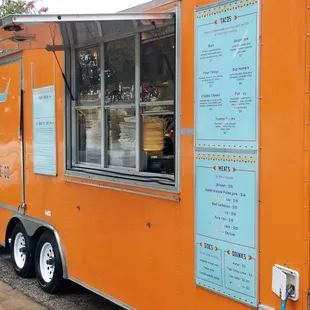 an orange food truck parked on the side of the road