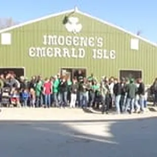 a crowd of people standing in front of a green building