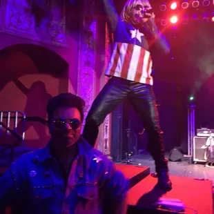 a man standing on a stage with his arms in the air