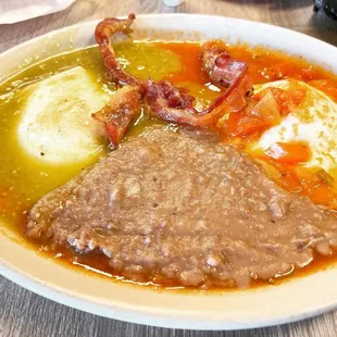 a bowl of soup with meat, eggs, and potatoes