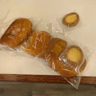 three pastries wrapped in plastic on a table