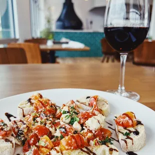 a plate of appetizers and a glass of red wine