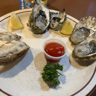 a plate of oysters with a side of ketchup