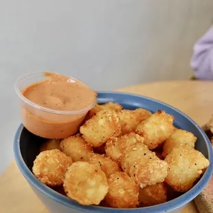 a bowl of tater tots and a sandwich