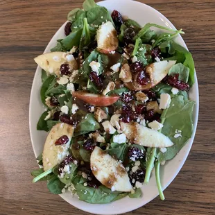 a plate of salad with apples, cranberries, and walnuts