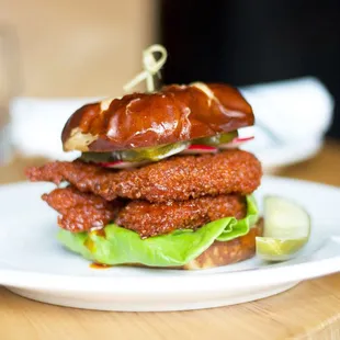 Nashville Hot Katsu Sandwich - Nashville hot chicken, &apos;Bama white sauce, pickles, greens, radish on a pretzel bun