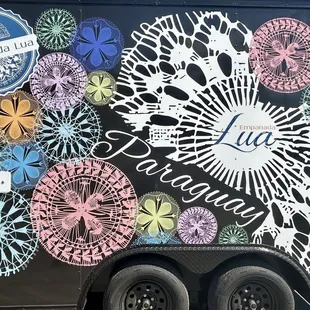 a black trailer with colorful flowers on the side
