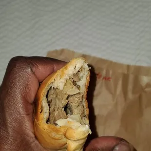 a hand holding a half eaten sandwich