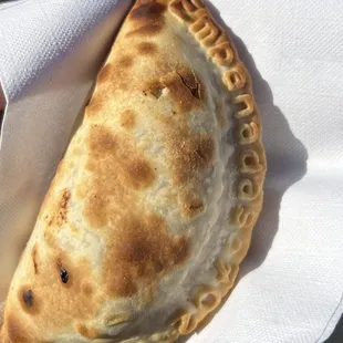 a hand holding an empanada