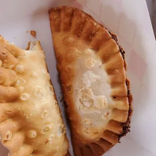 two empanadas in a paper container