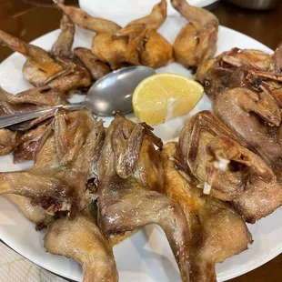 a plate of chicken wings with a lemon wedge