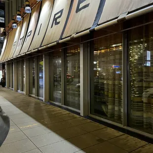 a woman walking down a sidewalk in front of a store