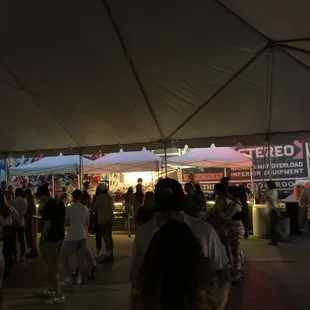 a crowd of people standing under a tent