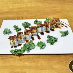 a plate of sushi with sauce and kale