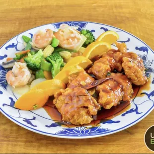 a plate of food with shrimp, broccoli, and orange slices