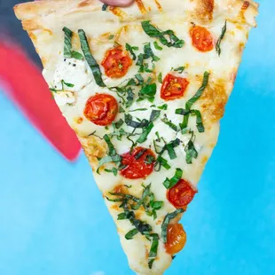 a hand holding a slice of pizza