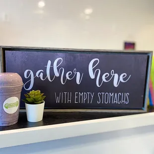 a cup of coffee and a sign that says gather here with empty stomachs