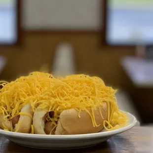 a plate of hot dogs covered in cheese