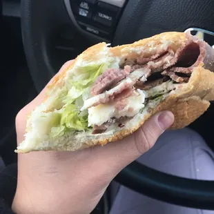 a hand holding a sub sandwich