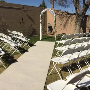 Folding chairs, carpet runner and arch set-up by Enchanted Occasions Event Rentals