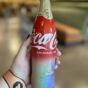 a hand holding a coca cola bottle