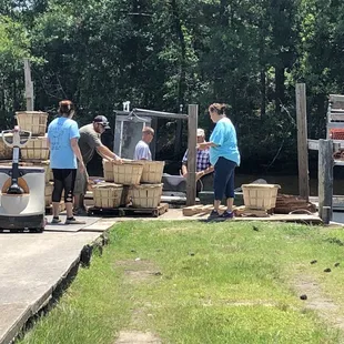 a group of people loading baskets onto a boat