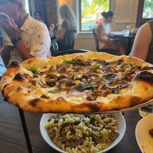 Mushroom pizza and fusili with mushrooms, broccolini, onions, and cheese.