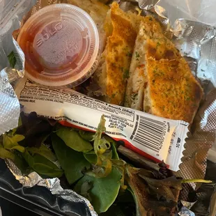 a sandwich and salad wrapped in foil