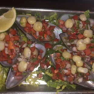 a tray of mussels with a lemon wedge