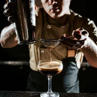 a bartender pouring a drink into a glass