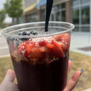a hand holding a cup of fruit