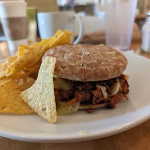 Jackfruit bbq sandwich with tortilla chips with sriracha sauce.