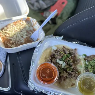 Carne Asada tacos. One with corn tortilla, one with flour and a side of pinto beans.