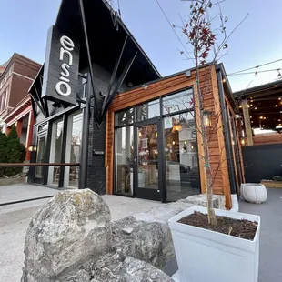 the exterior of a restaurant with a large rock in front of it