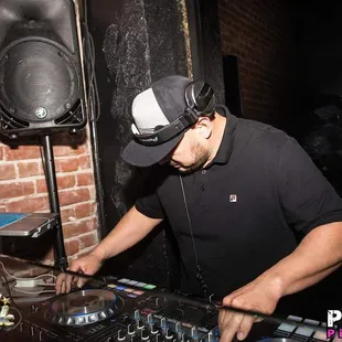 a dj mixing music in front of a brick wall