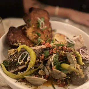 a bowl of clams, bread, and vegetables