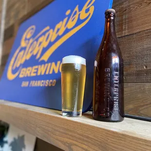 a glass of beer and a bottle on a shelf