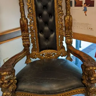 a gold throne with a black leather seat
