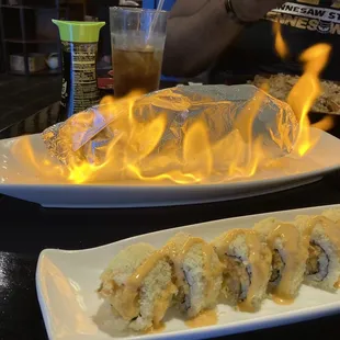 Atomic Bomb Roll (the one on fire). It is crazy delicious. It&apos;s a spicy tuna and cream roll with a smoky taste.