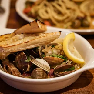 a bowl of clams and a lemon wedge