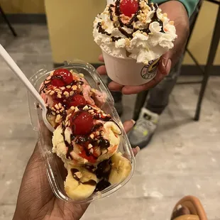 a hand holding two ice cream sundaes