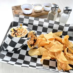 a sandwich and chips on a checkered tray