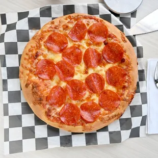 a pepperoni pizza on a checkered napkin