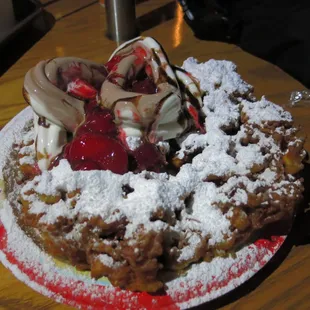 funnel cake with chocolate ice cream, strawberries, and chocolate syrup
